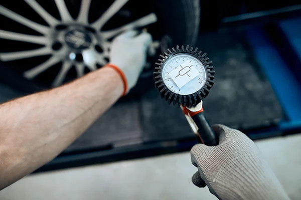 Technician checking tire pressure with gauge
