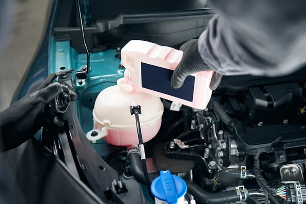 Technician topping off coolant reservoir with bottle