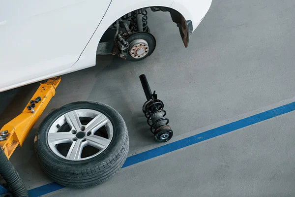 Shock removed from vehicle on ground next to tire and yellow lift
