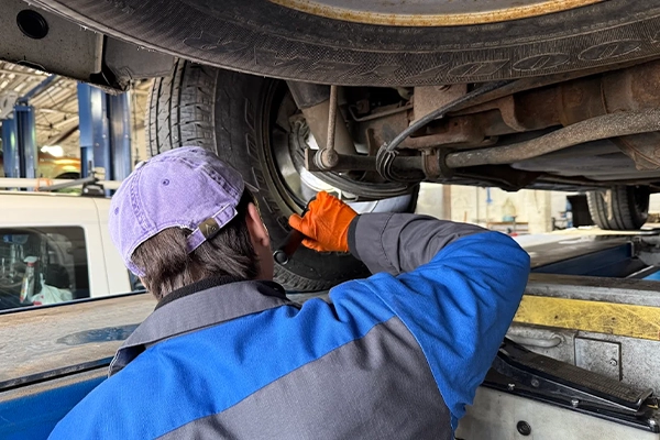 Technician inspecting behind wheel of vehicle on lift