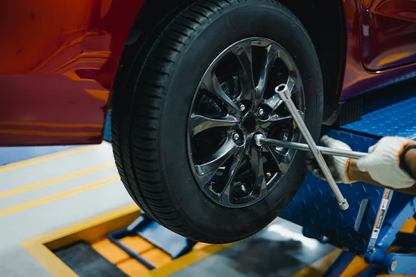 Technician removing wheel and tire from vehicle